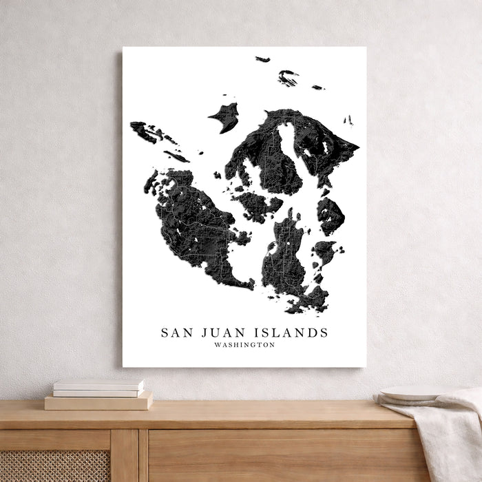 Map of San Juan Islands, Washington on a white wall above a wooden shelf.