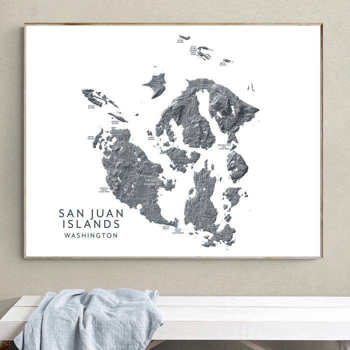 Framed map of San Juan Islands, Washington on a wall above a white surface.