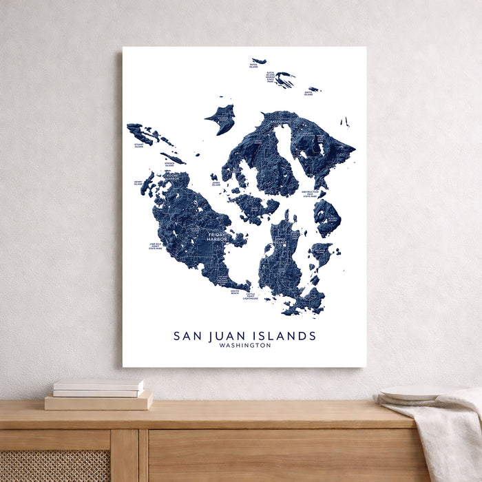 Map of San Juan Islands, Washington on a white wall above a wooden shelf.