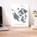 Map of San Juan Islands, Washington on a white background, displayed on a wooden desk with a laptop and plant.