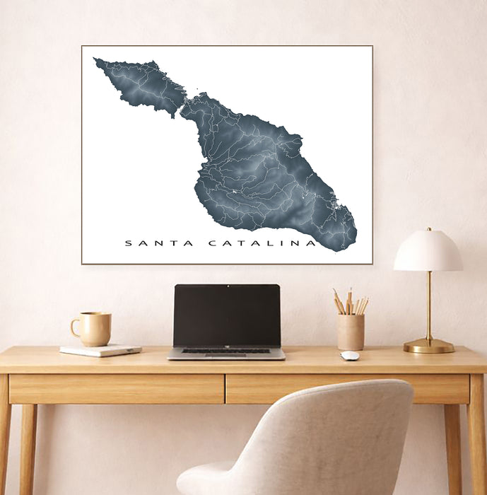Framed map of Santa Catalina on a wall above a desk with a laptop and lamp.