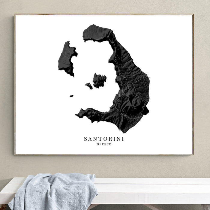 Framed map of Santorini, Greece on a wall above a white bench.