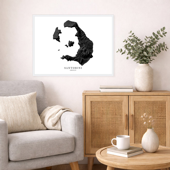 Framed map of Santorini on a wall above a sofa and side table with decor items.