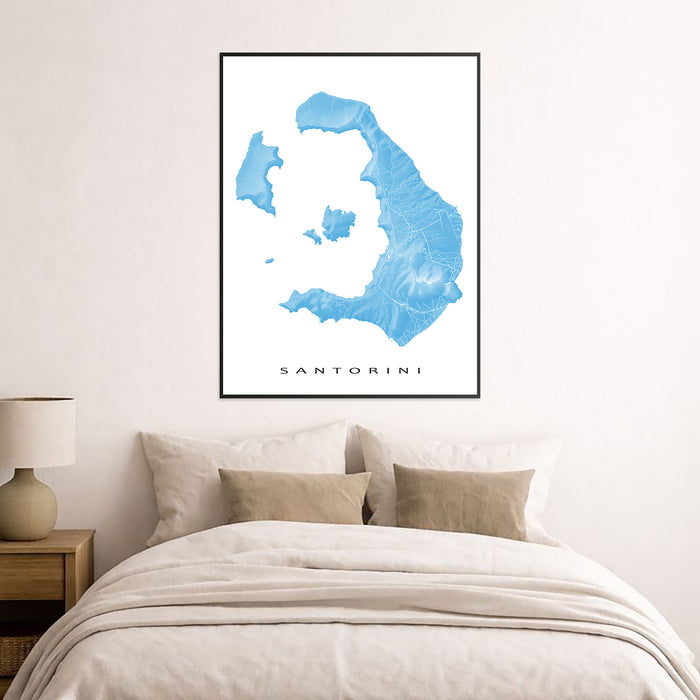 Framed map of Santorini on a wall above a bed with beige bedding.
