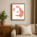 Framed map of Santorini on a wall above a sofa with a plant beside it.
