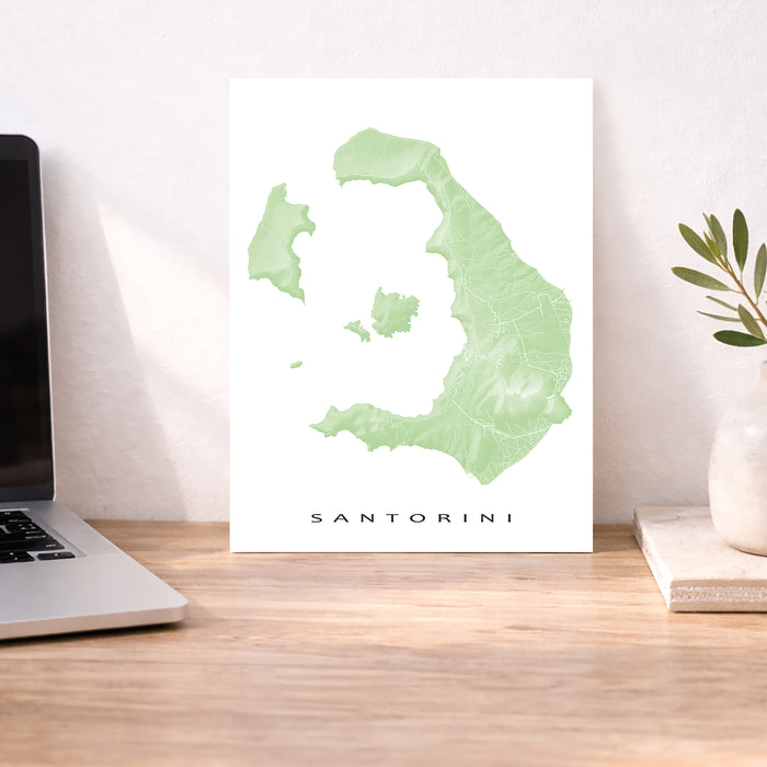 Map of Santorini on a desk with a laptop and plant
