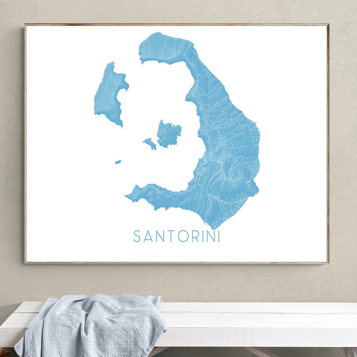 Framed map of Santorini on a wall above a white bench.