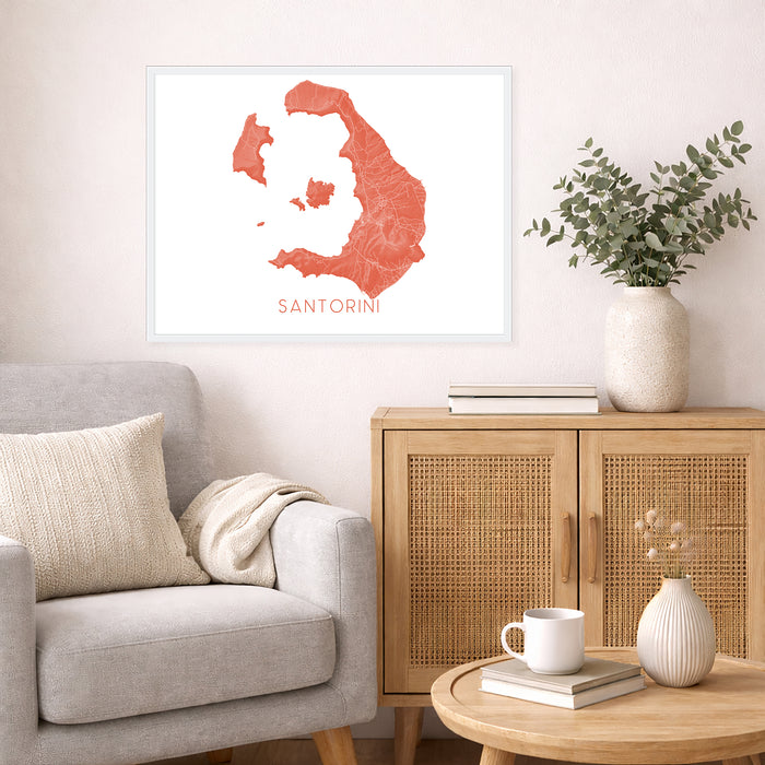 Living room with a map of Santorini on the wall, a vase with plants, and a coffee table with books and a mug.