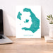 Map of Santorini on a desk with a laptop and plant