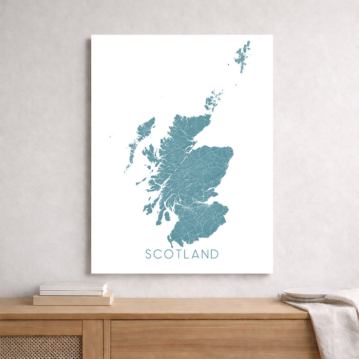 Map of Scotland on a white wall above a wooden shelf.
