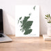 Map of Scotland on a white background next to a laptop on a wooden desk.