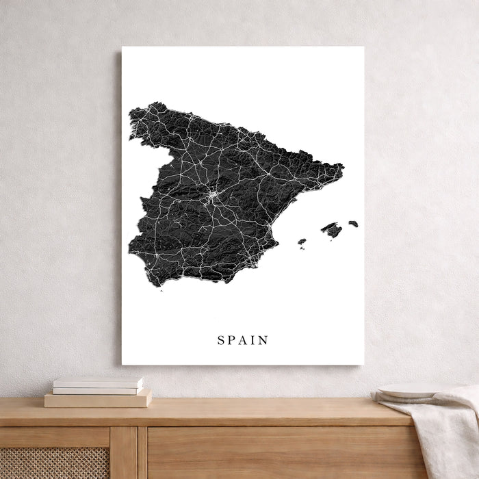 Map of Spain on a white wall above a wooden shelf.