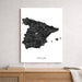 Map of Spain on a white wall above a wooden shelf.