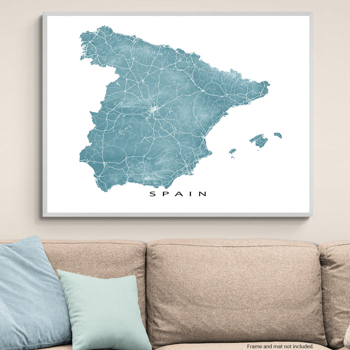Map of Spain on a wall above a beige sofa with light blue cushions.
