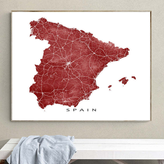 Framed map of Spain on a wall above a white surface.