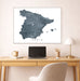 Map of Spain on a wall above a desk with a laptop and lamp.