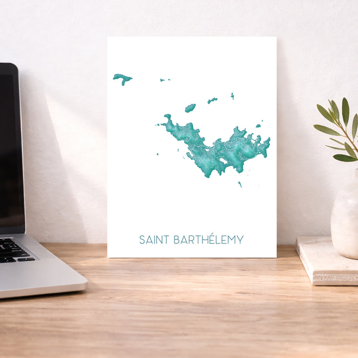 Map of Saint Barthélemy on a desk with a laptop and plant