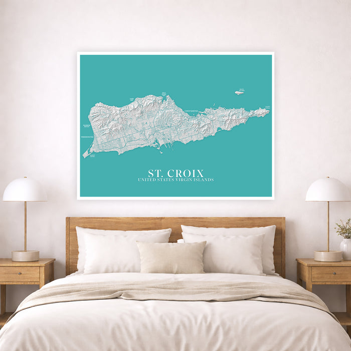 Map of St. Croix on a teal background above a bed in a bedroom.