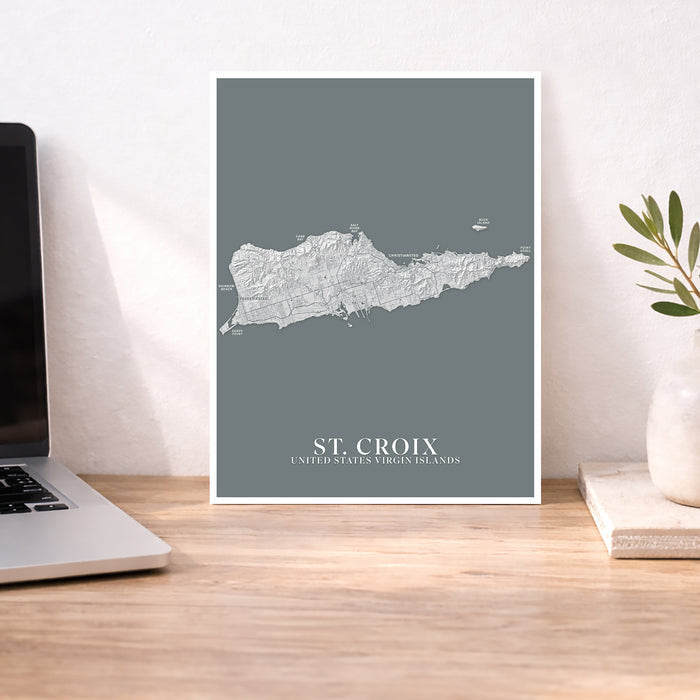 Map of St. Croix, US Virgin Islands on a wall above a desk with a laptop and plant.