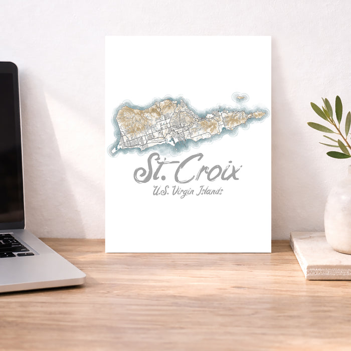 Map of St. Croix, U.S. Virgin Islands on a white background next to a laptop on a wooden desk.