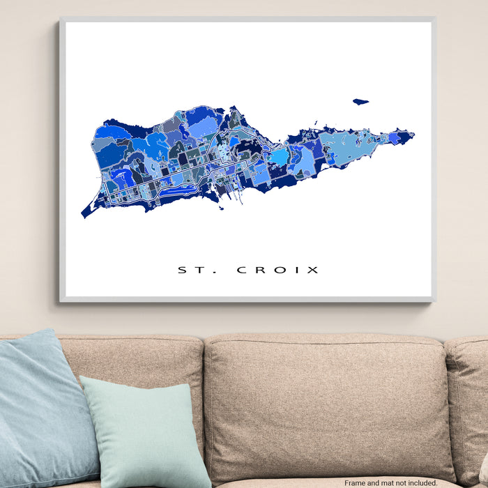 Framed map of St. Croix on a wall above a beige sofa with light blue pillows.