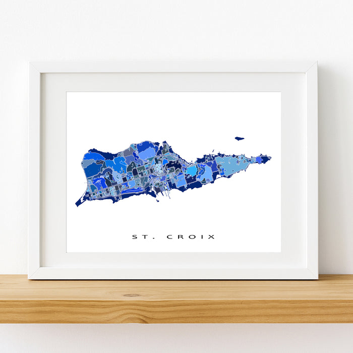 Framed map of St. Croix with a white border on a wooden surface.