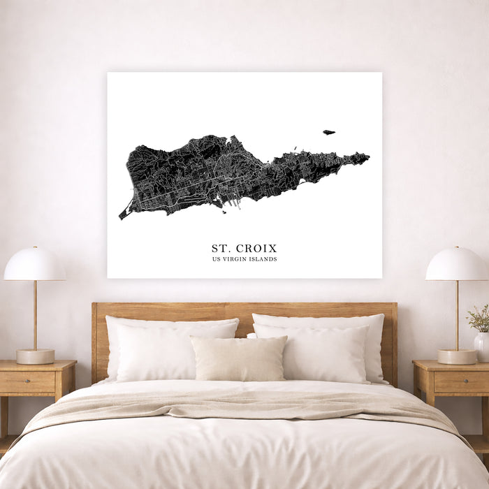Framed map of St. Croix on a wall above a bed in a bedroom.