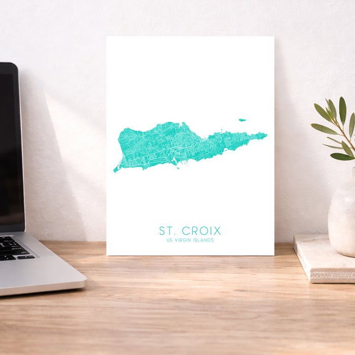 Map of St. Croix on a white background next to a laptop on a wooden desk.