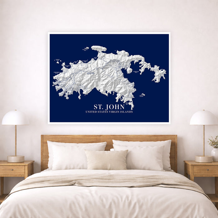 Framed map of St. John, United States Virgin Islands on a wall above a bed.