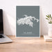 Map of St. John, United States Virgin Islands on a gray background in a white frame on a wooden desk.