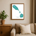 Framed map of St. Kitts and Nevis on a wall above a beige sofa with a plant beside it.