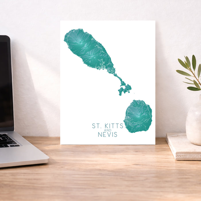 Map of St. Kitts and Nevis on a desk with a laptop and plant.