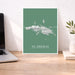 Map of St. Thomas on a green background in a white frame on a desk.