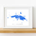 Framed map of St. Thomas on a white wall with a wooden shelf.