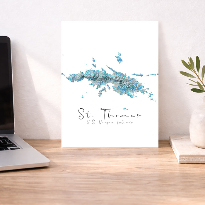 Map of St. Thomas, U.S. Virgin Islands on a desk with a laptop and plant.