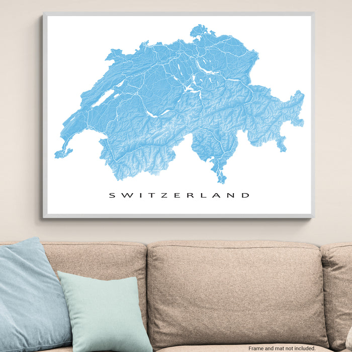 Framed map of Switzerland on a wall above a beige sofa with light blue pillows.