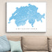 Framed map of Switzerland on a wall above a beige sofa with light blue pillows.