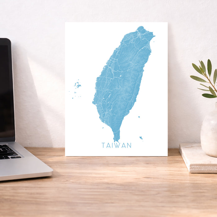 Map of Taiwan on a desk with a laptop and plant