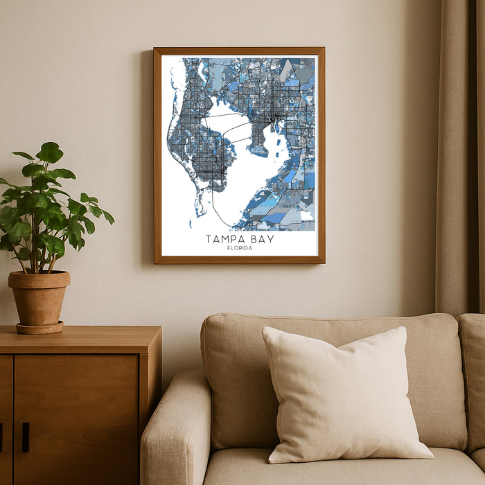 Framed map of Tampa Bay, Florida on a wall above a beige sofa with a plant beside it.