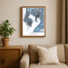 Framed map of Tampa Bay, Florida on a wall above a beige sofa with a plant beside it.