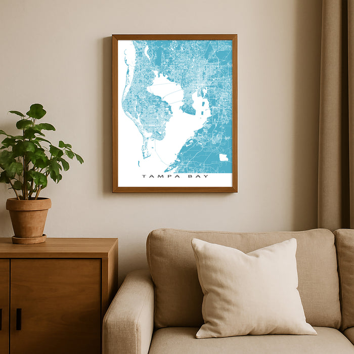 Framed map of Tampa Bay on a wall above a beige sofa with a plant beside it.
