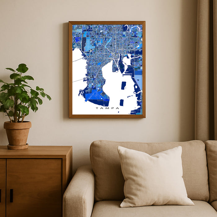 Framed map of Tampa on a wall above a beige sofa with a plant beside it.