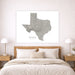 A large white canvas wall art print featuring a gray topographic map of Texas with the word 'TEXAS' below, displayed above a neatly made bed in a modern bedroom setting.