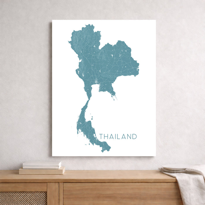 Map of Thailand on a white wall above a wooden cabinet.