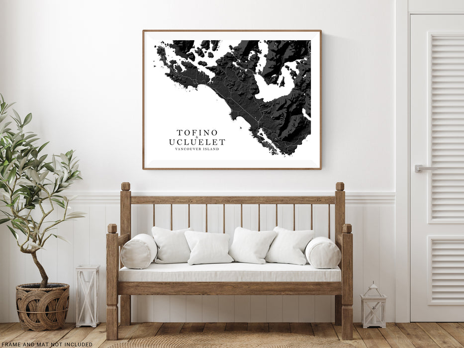 Framed black and white map of Tofino on a wall above a wooden bench with white cushions.