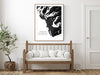 Wooden bench with white cushions in a room with a framed black and white map of Tofino on the wall.