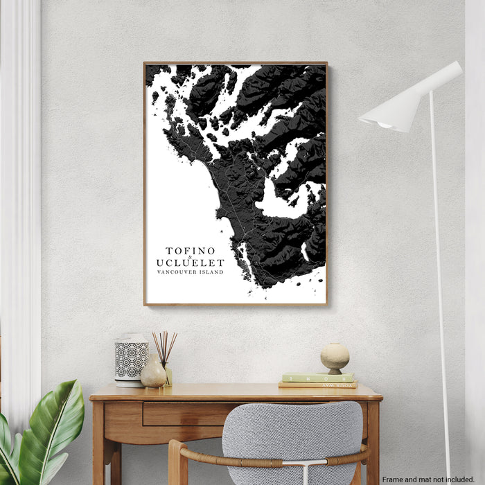 Framed black and white abstract art print on a wall above a desk.