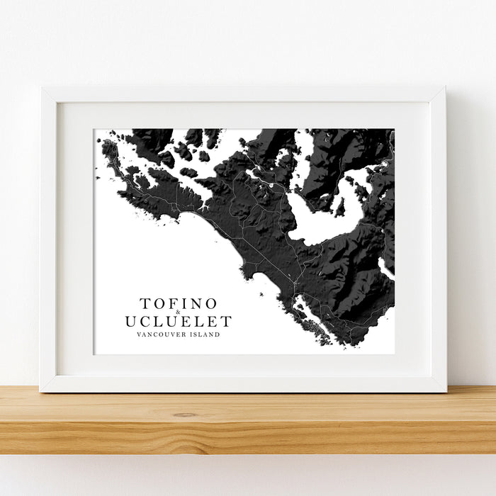 Framed map print of Tofino and Ucluelet on Vancouver Island, displayed on a wooden surface.