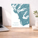 Map of Tofino and Ucluelet on Vancouver Island displayed on a desk with a laptop and plant.