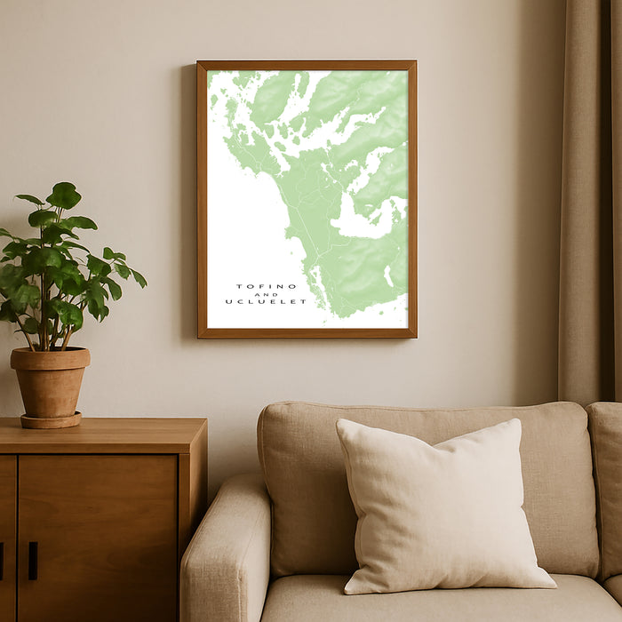 Framed map of Tofino on a wall above a beige sofa with a plant beside it.